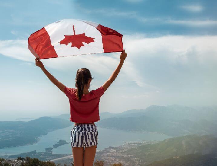 Girl standing on a mountain with a canadian flag above her head